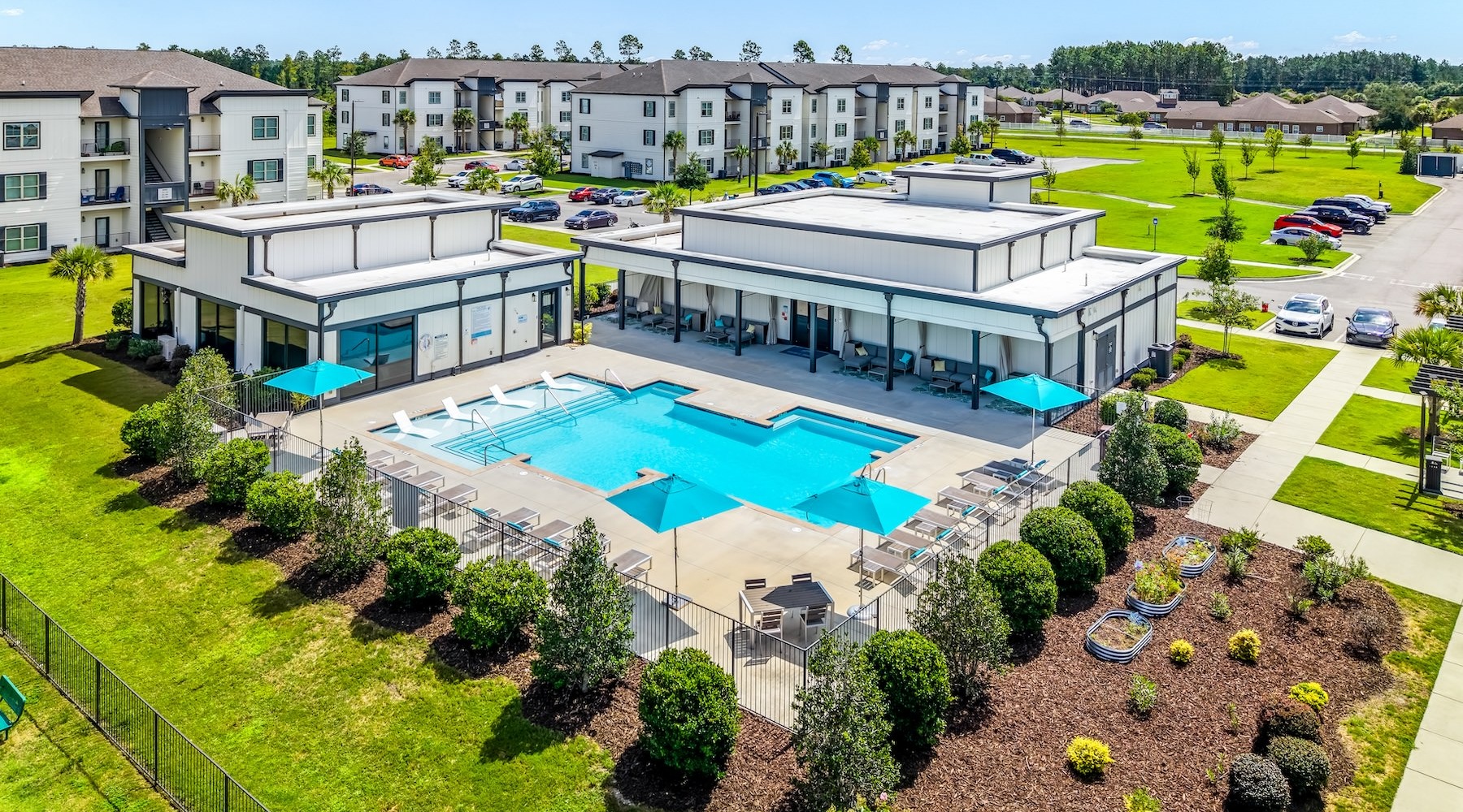 an aerial view of a pool with buildings and grass